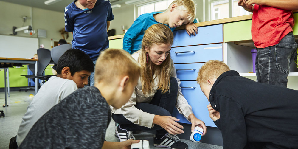 skolebørn der arbejder med naturfag og matematik på klassegulv
